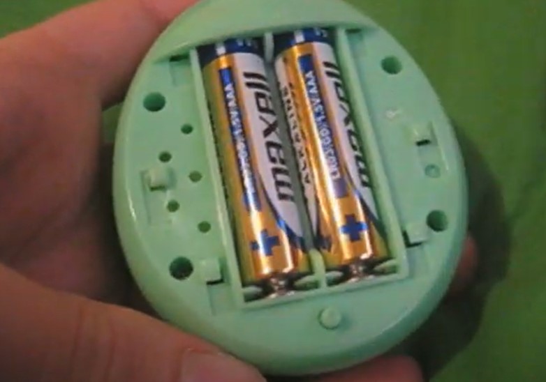 Screenshot from YouTube video of someone removing the battery from their Tamagotchi.